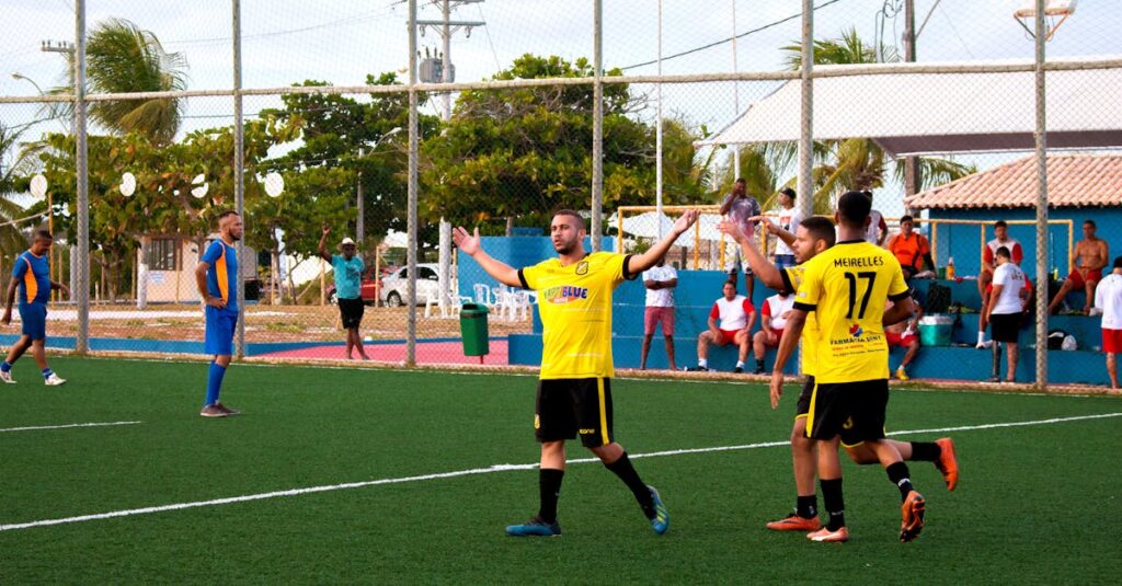 Amateur soccer team in yellow jerseys celebrates a goal during a match on an outdoor field.