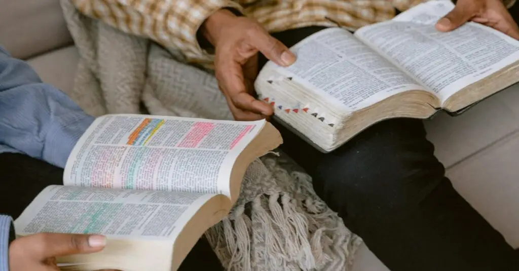 Two individuals sitting on a sofa reading and discussing the Bible indoors.